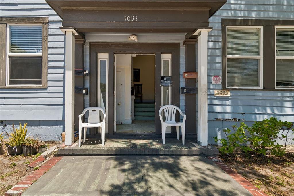 The exterior of a house entrance features a covered porch with two white plastic chairs — 1033 19TH AVENUE S, ST PETERSBURG, FL