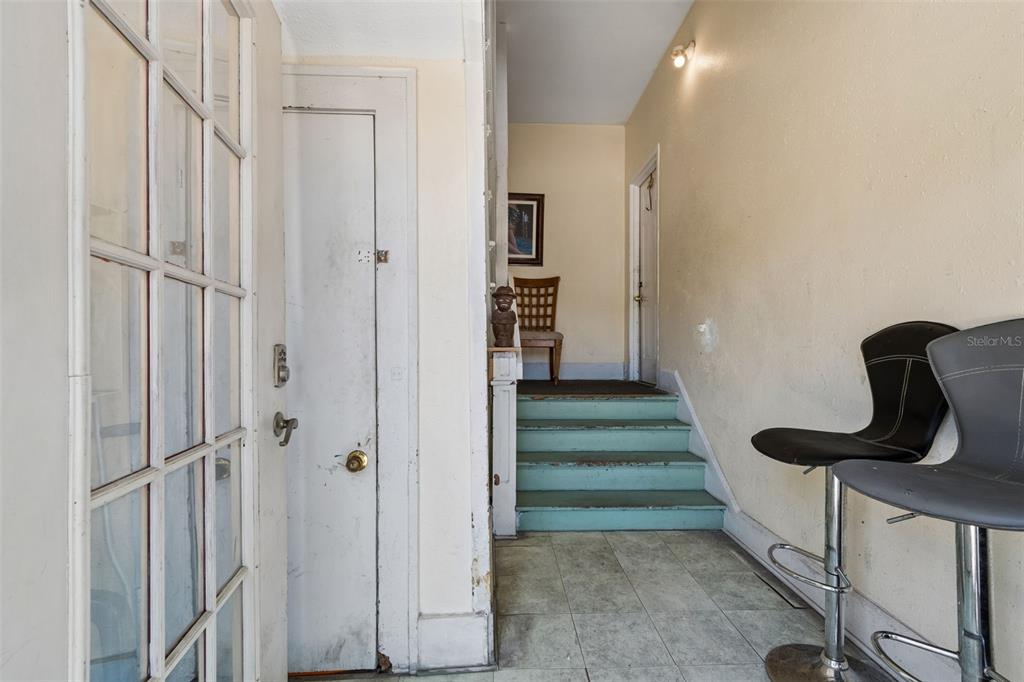 An interior entryway features a glass-paned door, a staircase with teal steps, and bar stools — 1033 19TH AVENUE S, ST PETERSBURG, FL