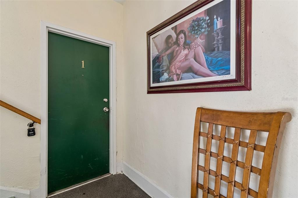 A green door labeled number one sits next to a framed painting and wooden chair — 1033 19TH AVENUE S, ST PETERSBURG, FL