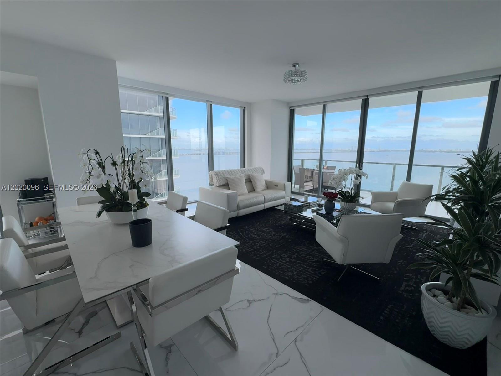 A modern living and dining room features white marble floors, floor-to-ceiling windows, and ocean views — 788 NE 23rd St # 1202, Miami FL 33137, MIAMI, FL