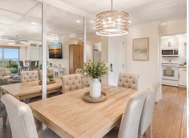 A dining room features a wooden table, upholstered chairs, a modern chandelier, and mirrored walls — 4505 S Ocean Blvd # 502, Highland Beach FL 33487, HIGHLAND BEACH, FL