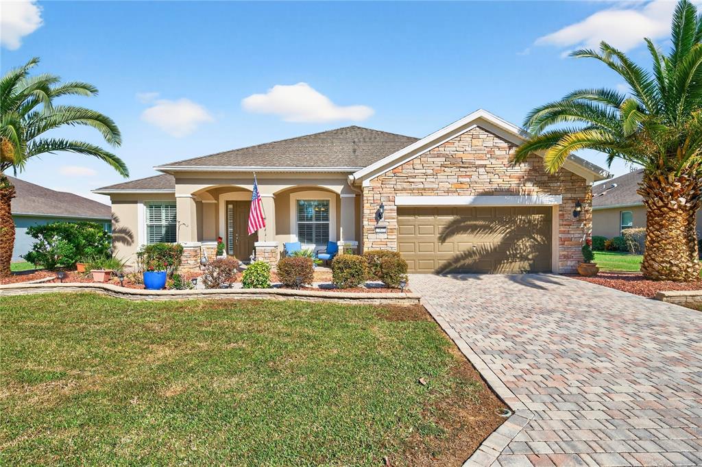 A single-story house with a stone facade, a two-car garage, and two palm trees — 7527 SW 97TH TERRACE ROAD, OCALA, FL