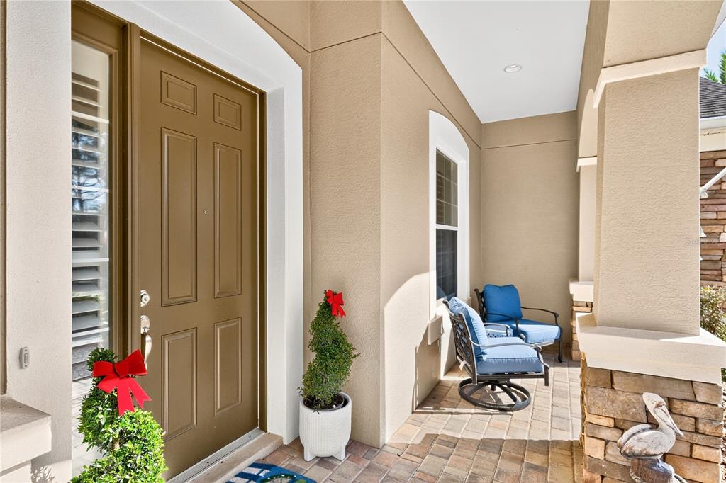 A covered front porch features a brown door, two chairs, and potted topiary plants — 7527 SW 97TH TERRACE ROAD, OCALA, FL