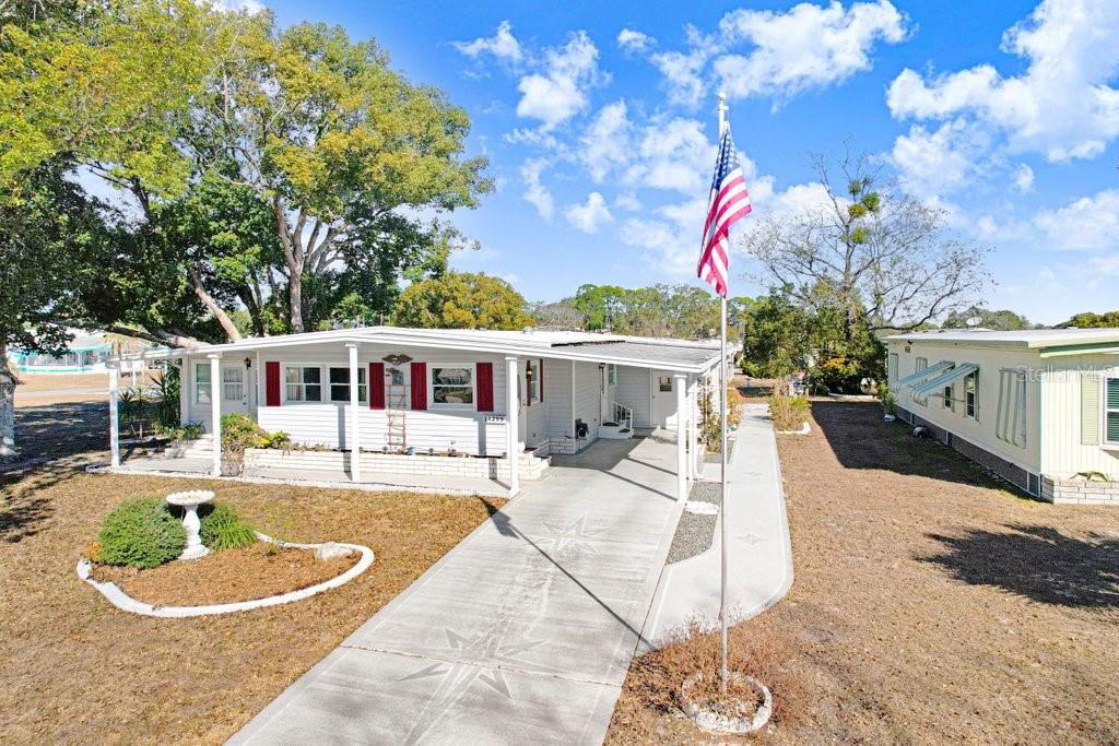 A single-story manufactured home with a concrete driveway, a flagpole, and a covered porch — 14299 NECTARINE STREET, BROOKSVILLE, FL