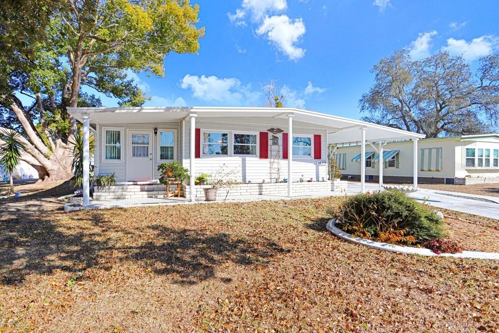 A single-story manufactured home with white siding, red shutters, and an attached carport — 14299 NECTARINE STREET, BROOKSVILLE, FL