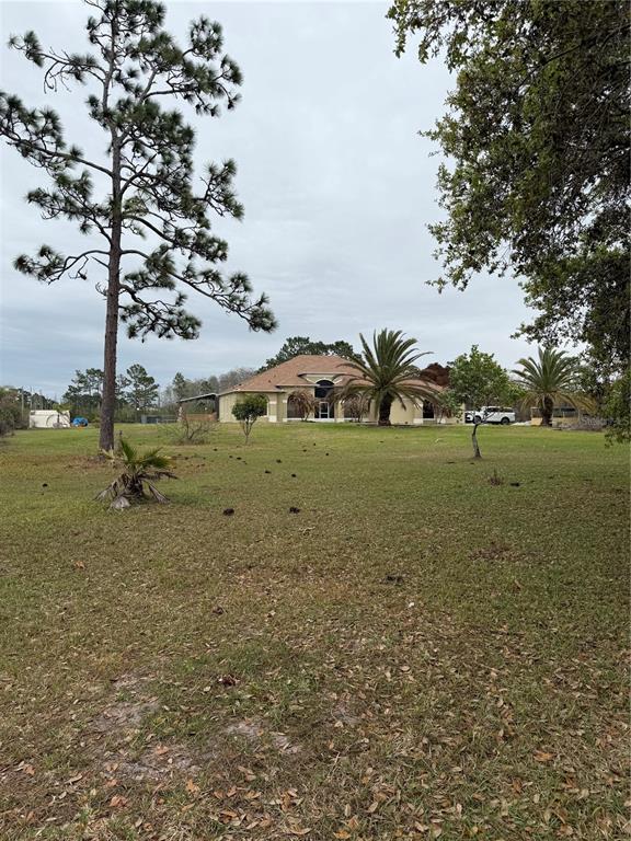 A tan single-story house sits in the distance on a large, grassy lot with trees — 3811 BANCROFT BOULEVARD, ORLANDO, FL