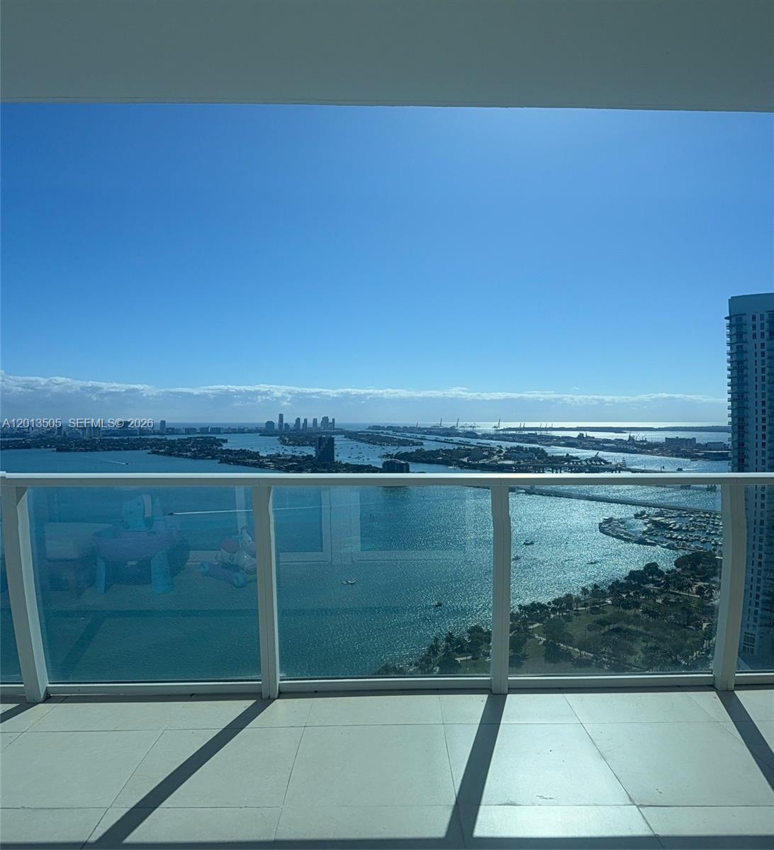 A balcony with a glass railing overlooks a bay, islands, and a distant city skyline — 2020 N Bayshore Dr # 3804, Miami FL 33137, MIAMI, FL