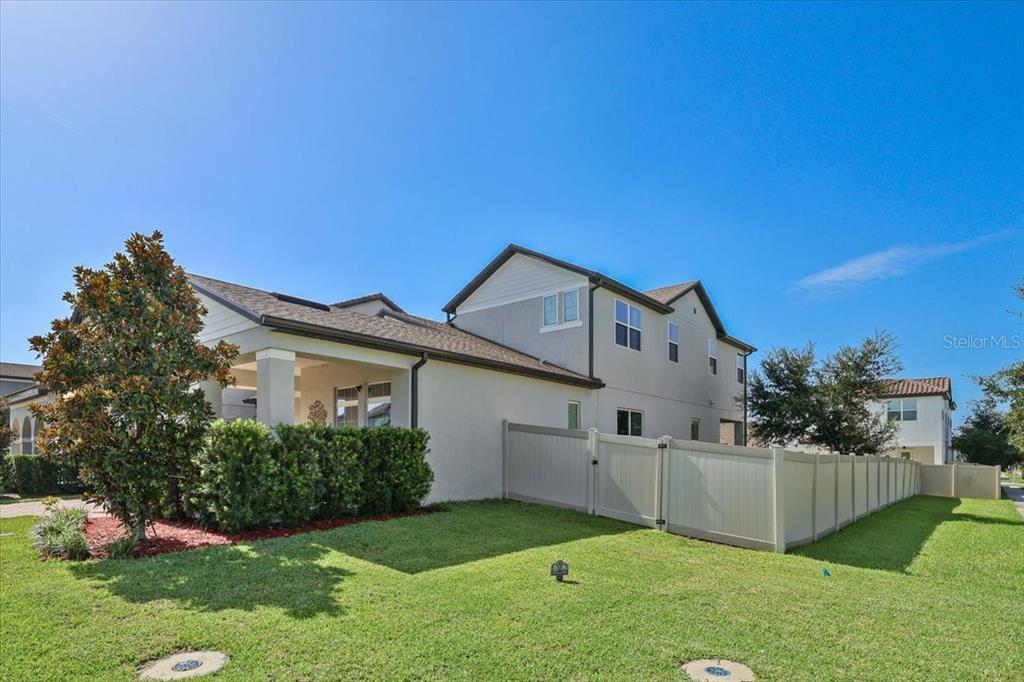 A two-story house with a covered patio, a white vinyl fence, and a green lawn — 9953 SUMMERLAKE GROVES STREET, WINTER GARDEN, FL