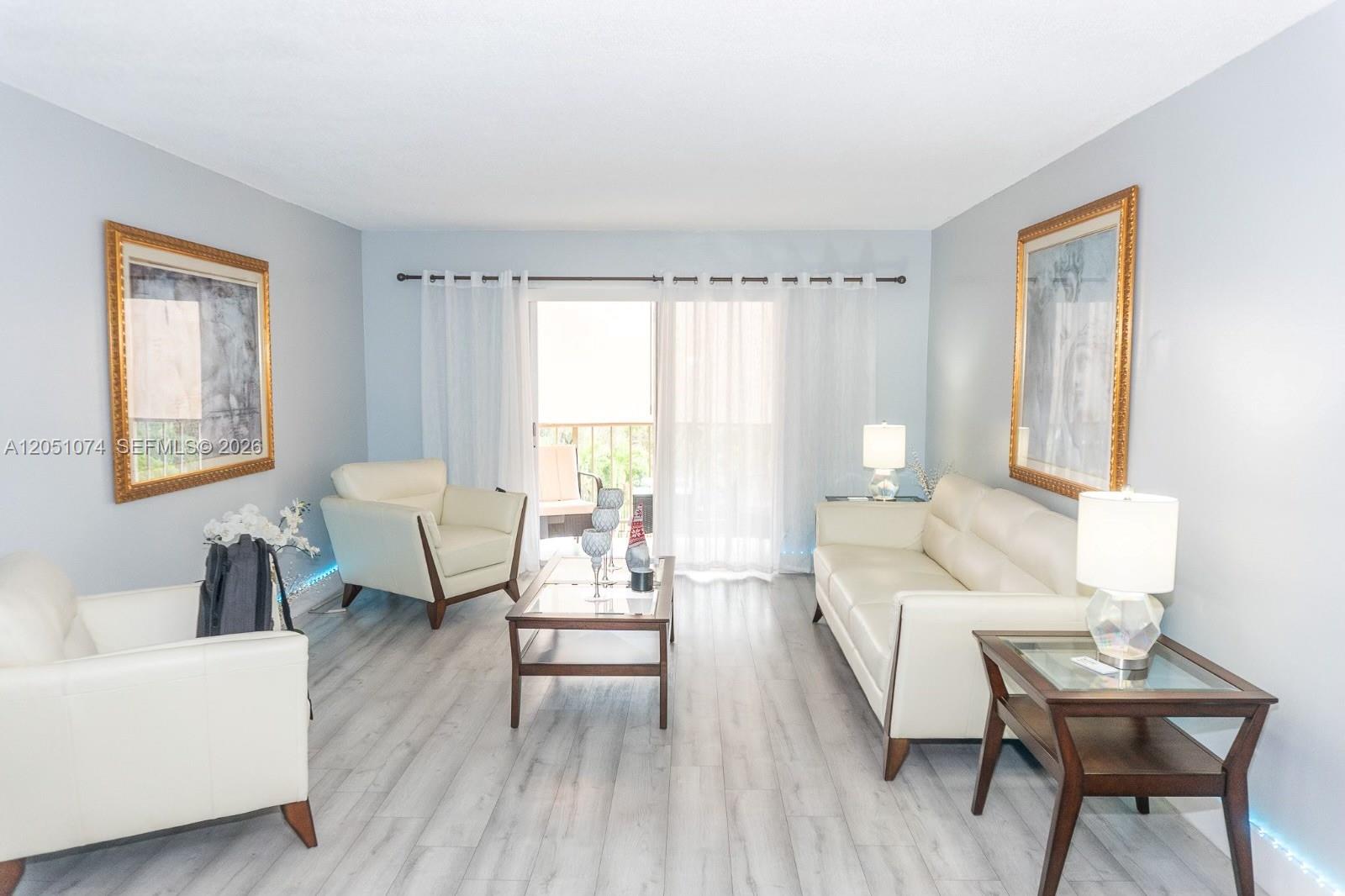 A living room features white leather furniture, a glass coffee table, and light wood flooring — 6190 W 19th Ave # 201, Hialeah FL 33012, HIALEAH, FL