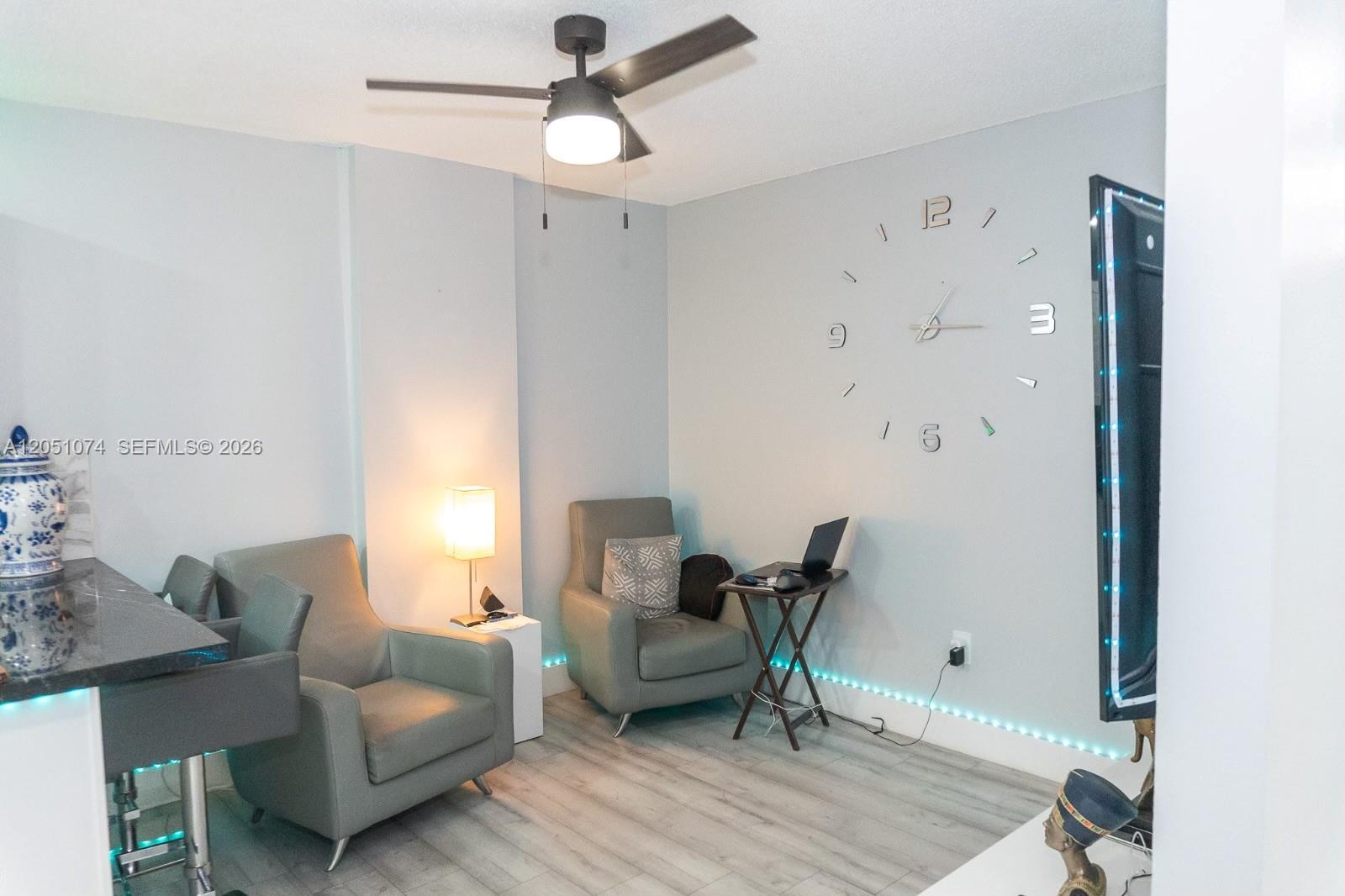 A living area features gray armchairs, a small desk, a wall clock, and LED floor lighting — 6190 W 19th Ave # 201, Hialeah FL 33012, HIALEAH, FL