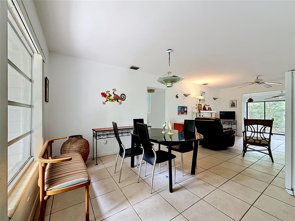 A dining area with tile flooring, a glass table, and a gecko wall decoration — 6330 EMERSON AVENUE S, ST PETERSBURG, FL
