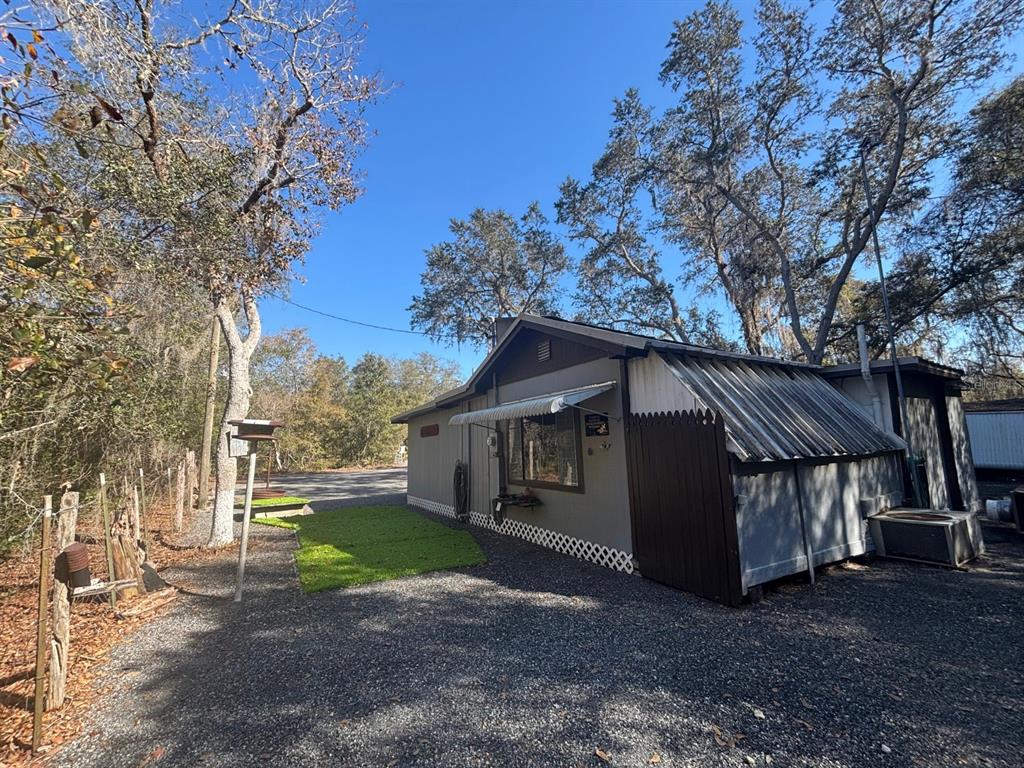 A gravel driveway leads to the side of a house with a metal roof — 14500 NE 188TH PLACE, FORT MC COY, FL