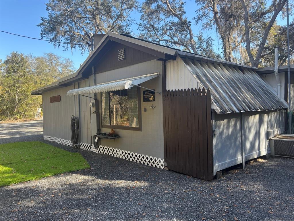 A single-story house with gray siding, a metal roof section, and a wooden privacy fence — 14500 NE 188TH PLACE, FORT MC COY, FL