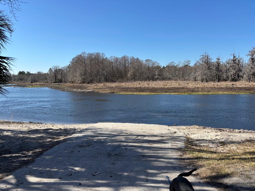 A concrete boat ramp leads into a river with a wooded shoreline in the background — 14500 NE 188TH PLACE, FORT MC COY, FL