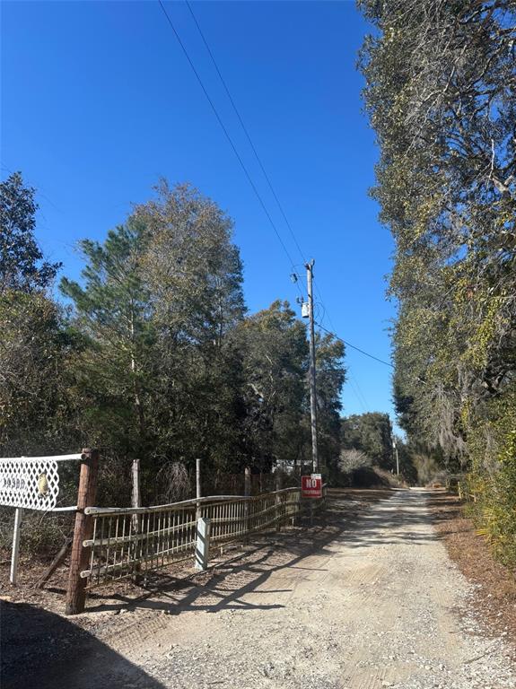 A dirt road leads past a wooden fence and a no trespassing sign toward trees — 14500 NE 188TH PLACE, FORT MC COY, FL