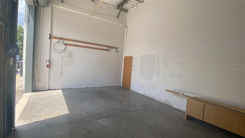 An empty industrial warehouse space features concrete floors, white walls, and a single wooden door — 1500 TROPIC PARK DRIVE UNIT 1582, SANFORD, FL