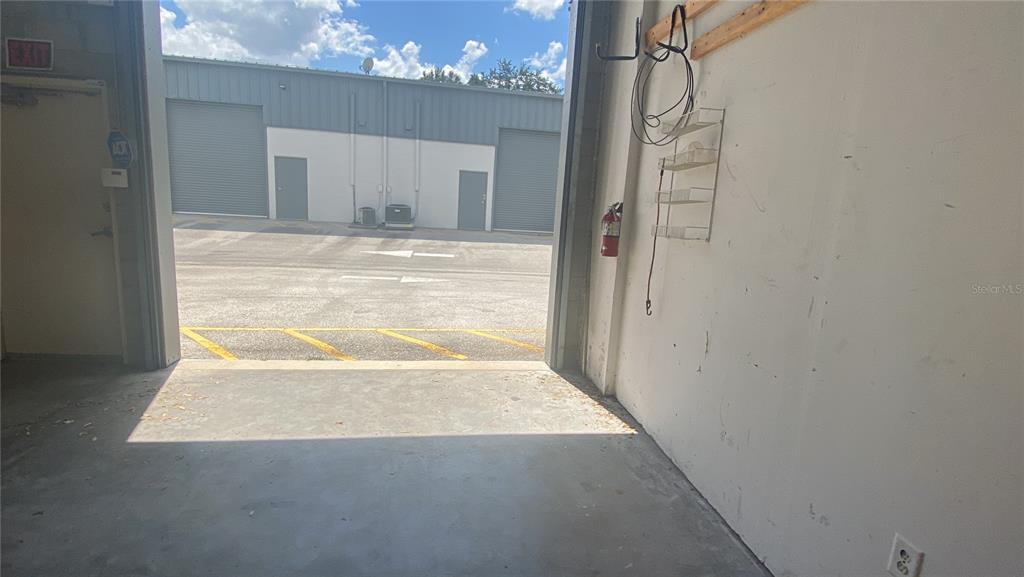An open warehouse bay looks out onto a paved parking lot with metal buildings — 1500 TROPIC PARK DRIVE UNIT 1582, SANFORD, FL
