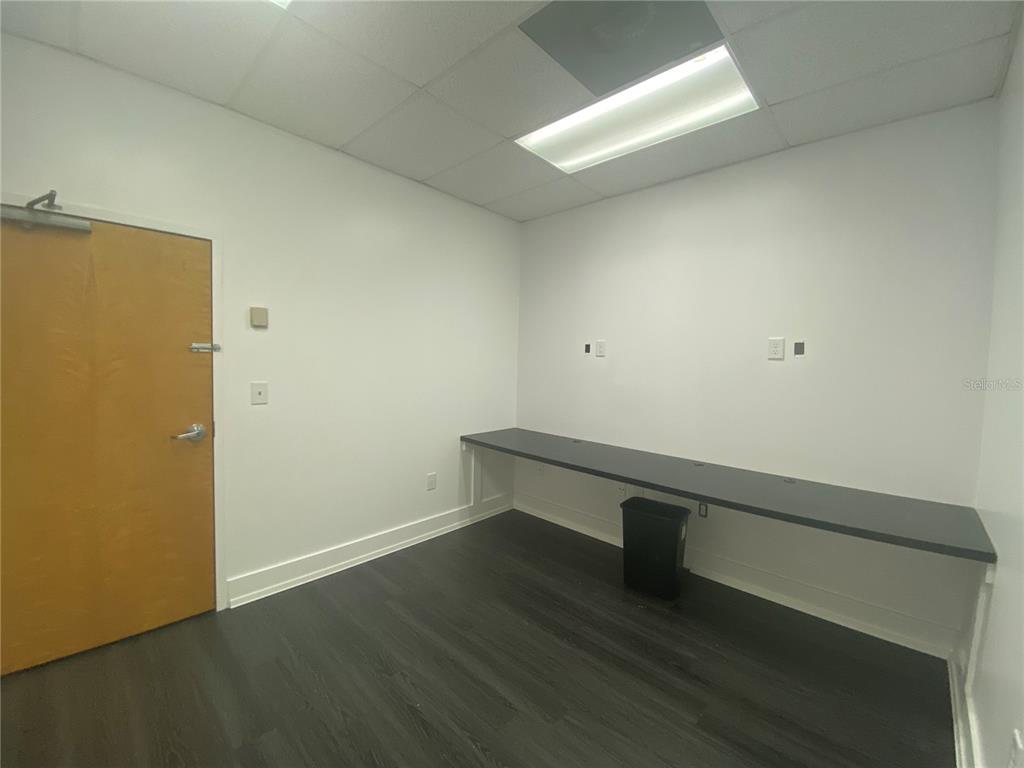 An empty office features a long black desk, white walls, and dark wood-look flooring — 1500 TROPIC PARK DRIVE UNIT 1582, SANFORD, FL