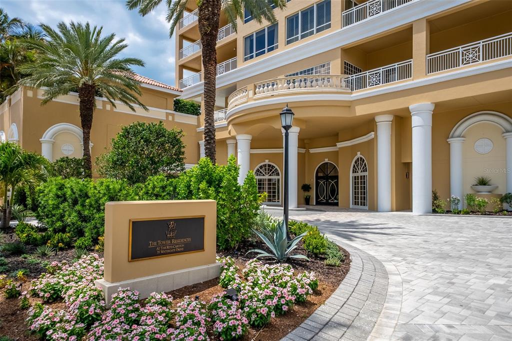 The exterior of a multi-story building features a paved driveway, landscaping, and a prominent sign — 35 WATERGATE DRIVE UNIT 502, SARASOTA, FL