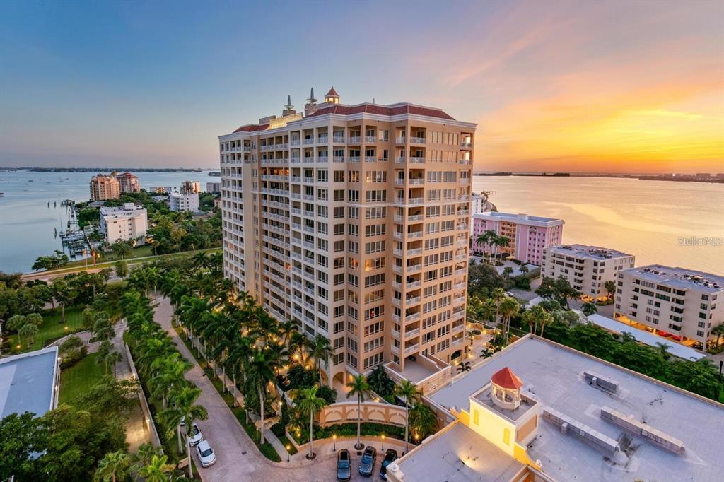 An aerial view of a tall residential building surrounded by palm trees and waterfront property — 35 WATERGATE DRIVE UNIT 502, SARASOTA, FL