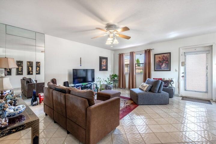 A living room features a brown sectional sofa, a television, and tile flooring — 657 Brittany N, Delray Beach FL 33446, DELRAY BEACH, FL
