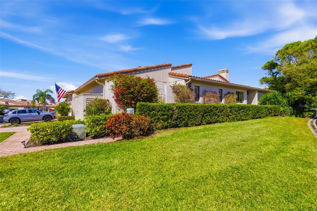 A beige house exterior features a two-car garage, a paved driveway, and an American flag — 2326 HARBOUR OAKS DRIVE, LONGBOAT KEY, FL