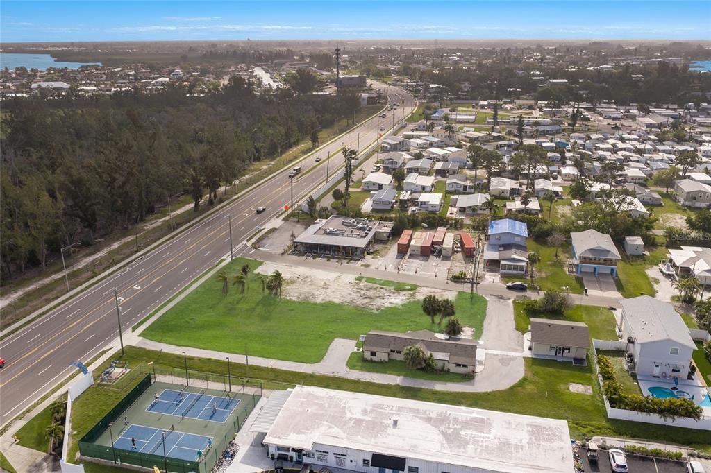 An aerial view shows a commercial property with tennis courts, a parking lot, and nearby houses — 10601-10611 CORTEZ ROAD W, BRADENTON, FL