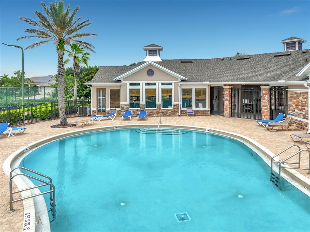 A swimming pool sits in front of a clubhouse with a stone facade and roof — 3678 PEACEPIPE WAY, CLERMONT, FL