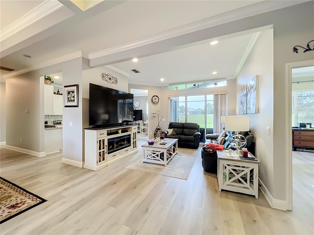 A living room features light wood flooring, a large television, and a fireplace console — 3678 PEACEPIPE WAY, CLERMONT, FL