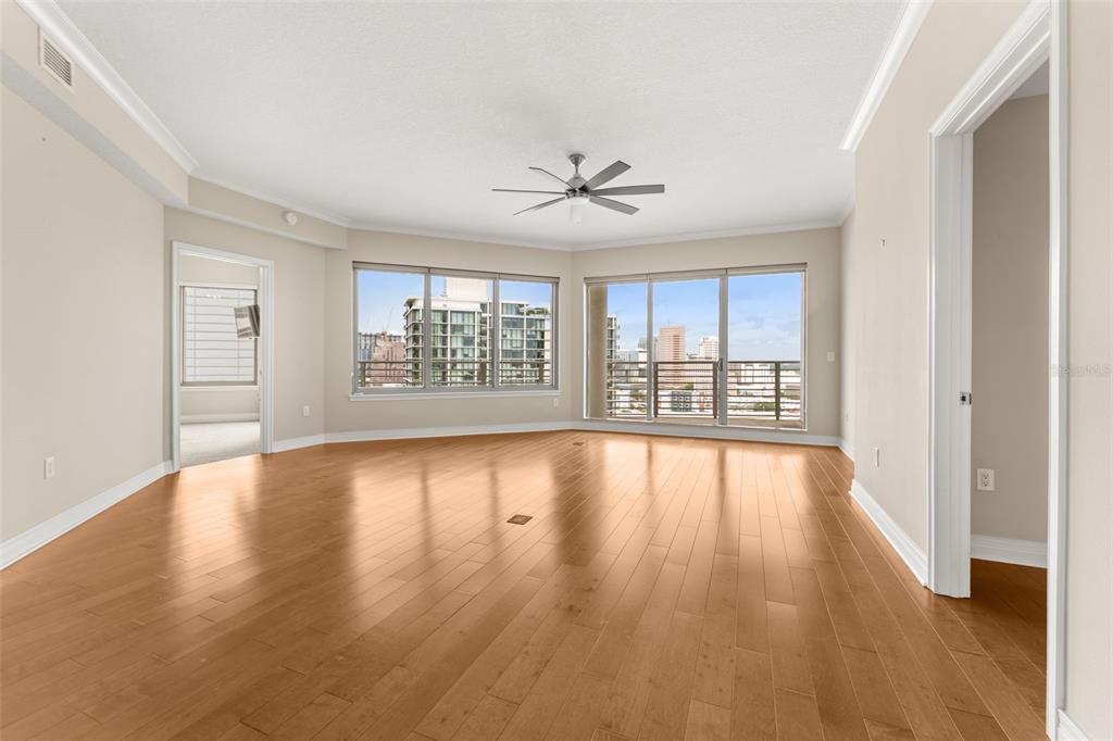 An empty living room with hardwood floors, a ceiling fan, and large windows overlooking city buildings — 449 S 12TH STREET UNIT 2005, TAMPA, FL
