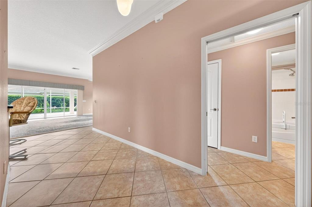 A tiled hallway leads to a living area with large windows and a bathroom doorway — 2612 MORVEN PARK WAY, THE VILLAGES, FL