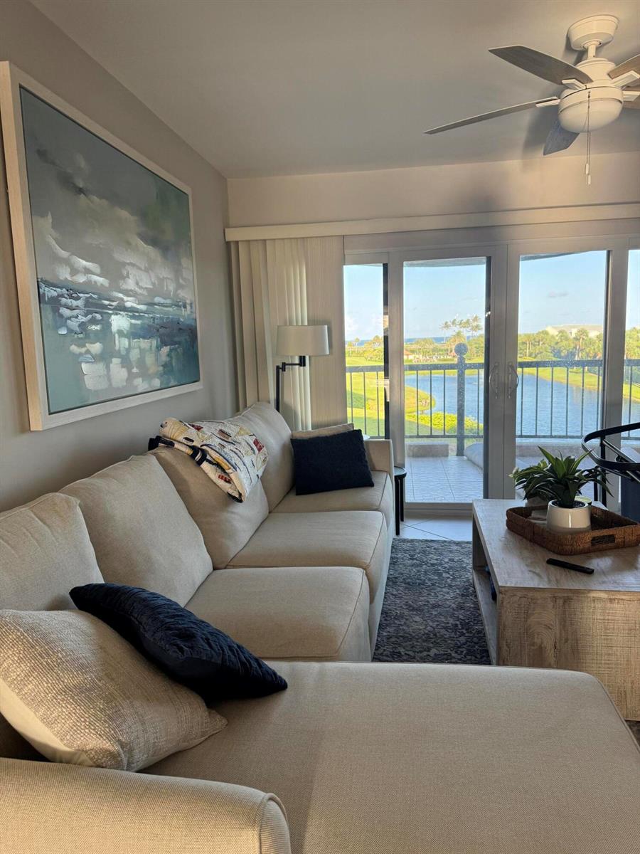 A living room with a sectional sofa, large abstract art, and a balcony overlooking water — 401 Ocean Bluffs Boulevard # 303, Jupiter FL 33477, JUPITER, FL