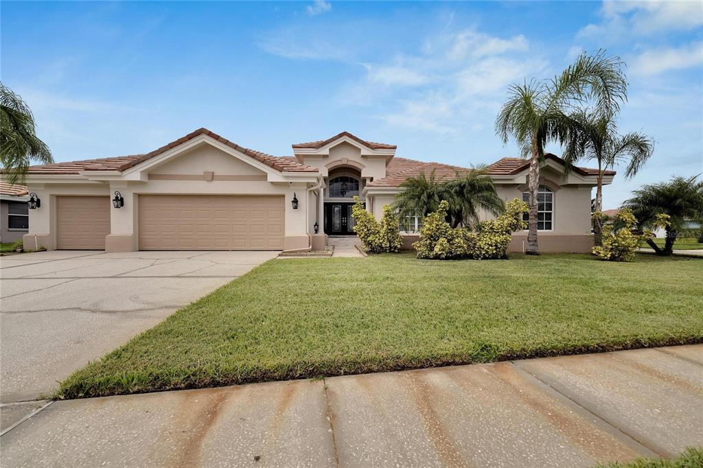 A single-story house with a beige stucco exterior, a three-car garage, and a tiled roof — 10301 MANTA WAY, TAMPA, FL