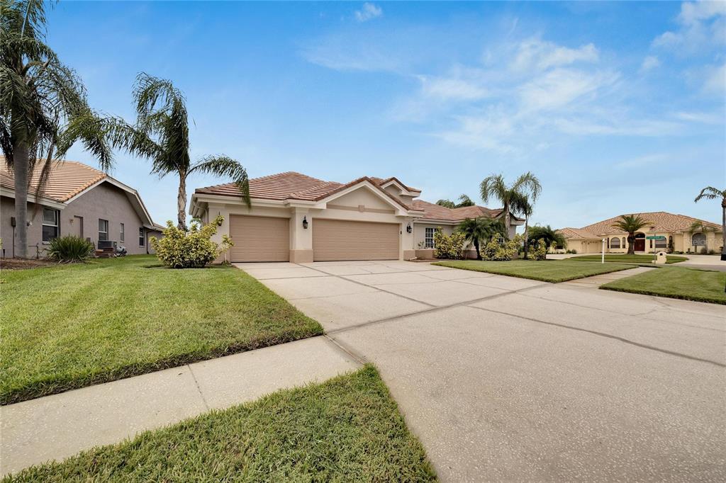 A single-story house with a three-car garage, a concrete driveway, and palm trees — 10301 MANTA WAY, TAMPA, FL