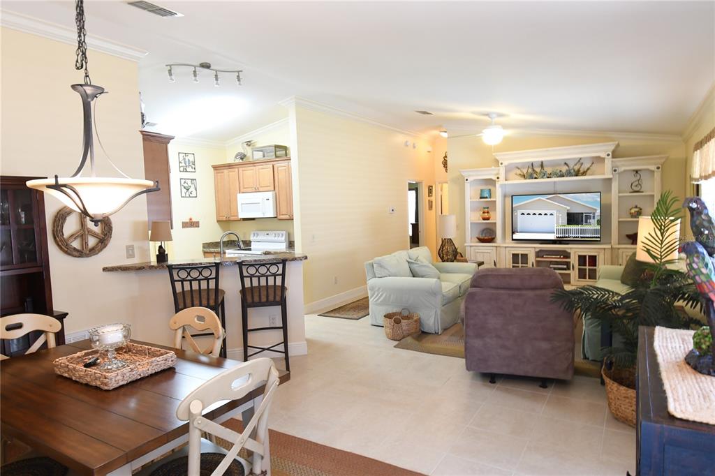 An open-concept living room and kitchen area with light-colored tile flooring and neutral walls — 2372 TRAVIS PLACE, THE VILLAGES, FL