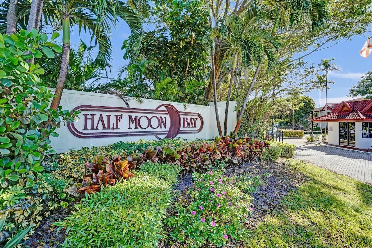 A sign for Half Moon Bay stands in front of lush landscaping and a building — 107 Half Moon Circle # H1, Hypoluxo FL 33462, HYPOLUXO, FL