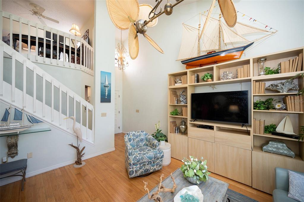 A living room features a high ceiling, a large wooden model ship, and built-in shelving — 1757 WINDSONG CIRCLE, FLAGLER BEACH, FL