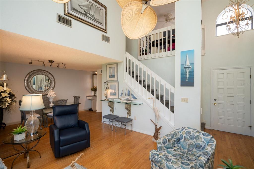 A living room with a staircase, hardwood floors, and a vaulted ceiling with a chandelier — 1757 WINDSONG CIRCLE, FLAGLER BEACH, FL