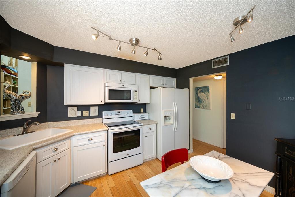 A kitchen with white cabinets, dark walls, a white stove, and a marble-topped table — 1757 WINDSONG CIRCLE, FLAGLER BEACH, FL