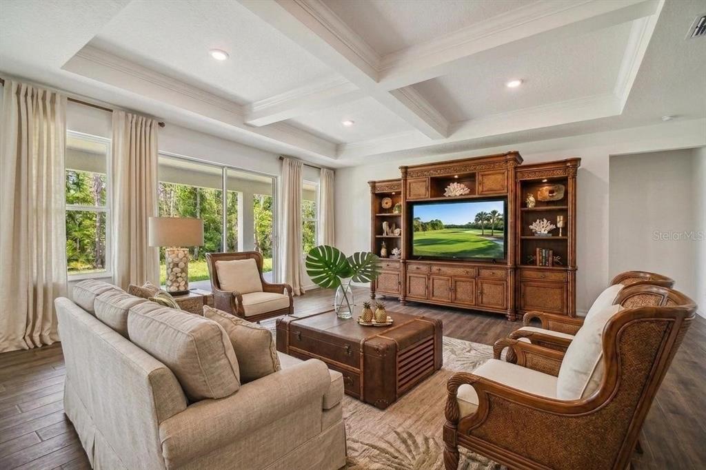 A living room features a coffered ceiling, large entertainment center, and views of a golf course — 5108 JENNINGS TRAIL, BROOKSVILLE, FL