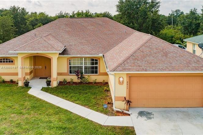 A single-story house with a tan exterior, a brown shingled roof, and an attached garage — 2611 65 st, Lehigh Acres FL 33971, LEHIGH ACRES, FL