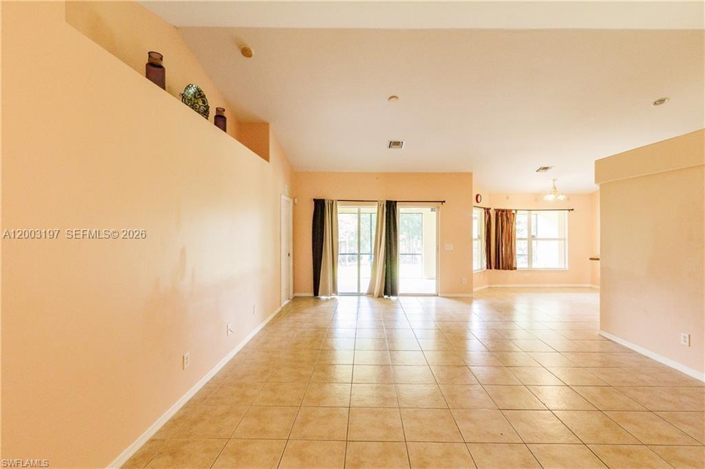 An open-concept living area features peach walls, tile flooring, and a sliding glass door — 2611 65 st, Lehigh Acres FL 33971, LEHIGH ACRES, FL