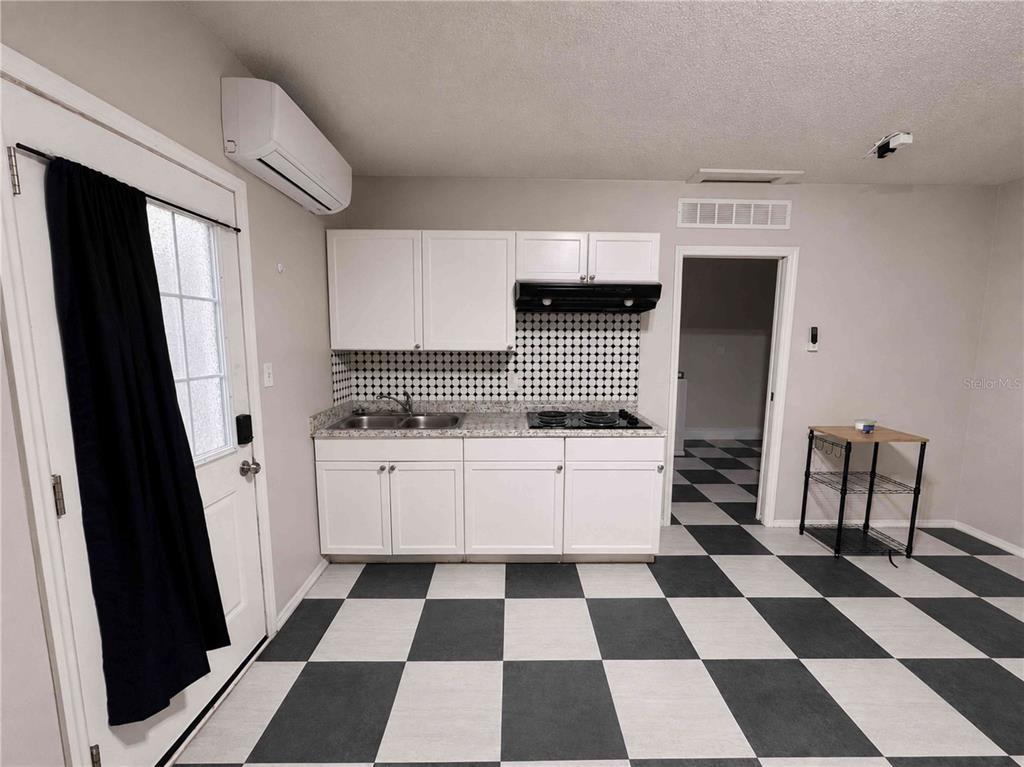 A kitchen features white cabinets, a black-and-white checkered floor, and a wall-mounted air conditioner — 7196 HARBOR HEIGHTS CIRCLE UNIT A, ORLANDO, FL