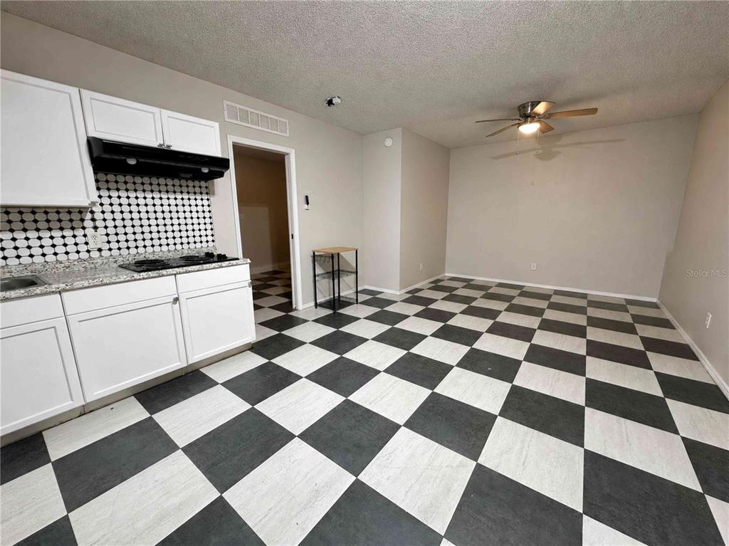 A kitchen and dining area with white cabinets, a black-and-white checkered floor, and a ceiling fan — 7196 HARBOR HEIGHTS CIRCLE UNIT A, ORLANDO, FL