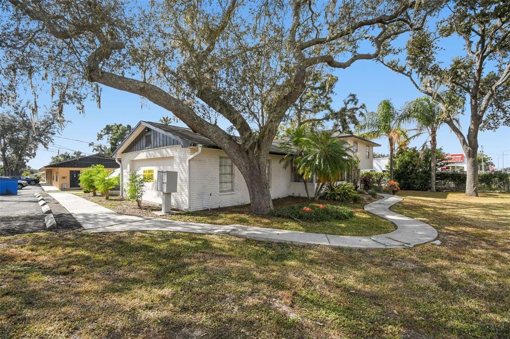 A white brick commercial building with a large oak tree and a curved concrete walkway — 855 E BRANDON BOULEVARD, BRANDON, FL
