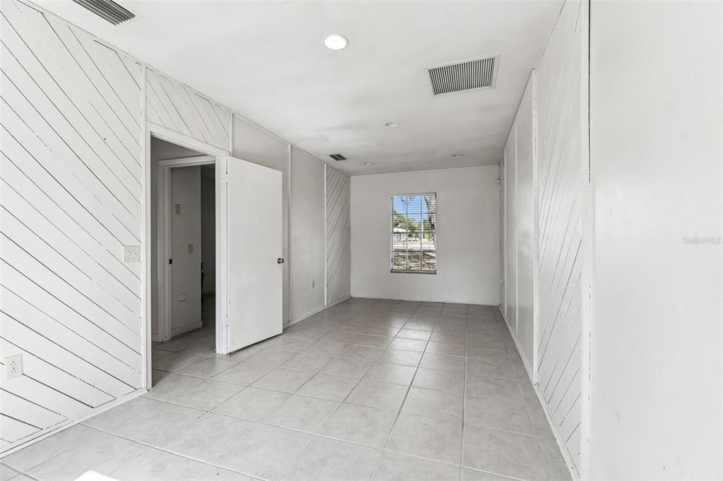 A room with white diagonal wood paneling, tiled floors, and a single window — 855 E BRANDON BOULEVARD, BRANDON, FL