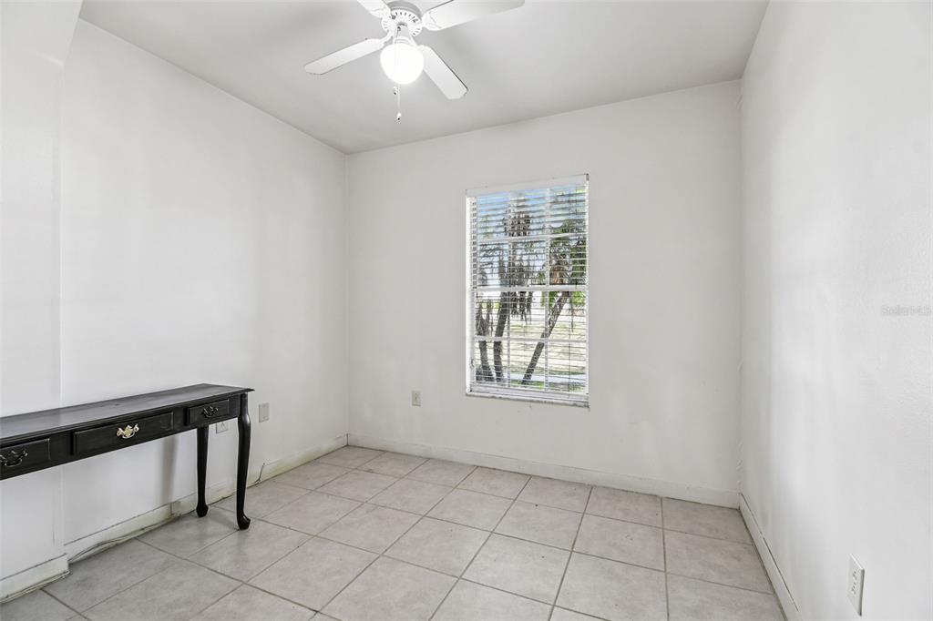A small, empty room with white walls, tile flooring, a ceiling fan, and a desk — 855 E BRANDON BOULEVARD, BRANDON, FL