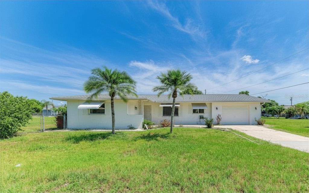 A single-story white house with a gray roof, two palm trees, and a concrete driveway — 20430 EDGEWATER DRIVE, PORT CHARLOTTE, FL
