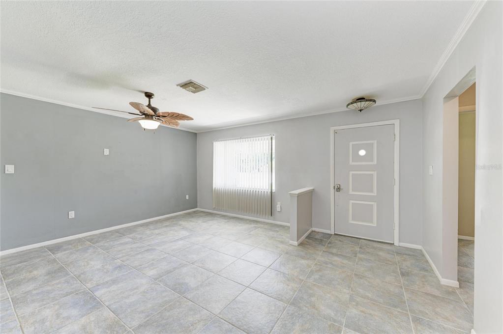 A living room with gray walls, tile flooring, a ceiling fan, and a front door — 20430 EDGEWATER DRIVE, PORT CHARLOTTE, FL