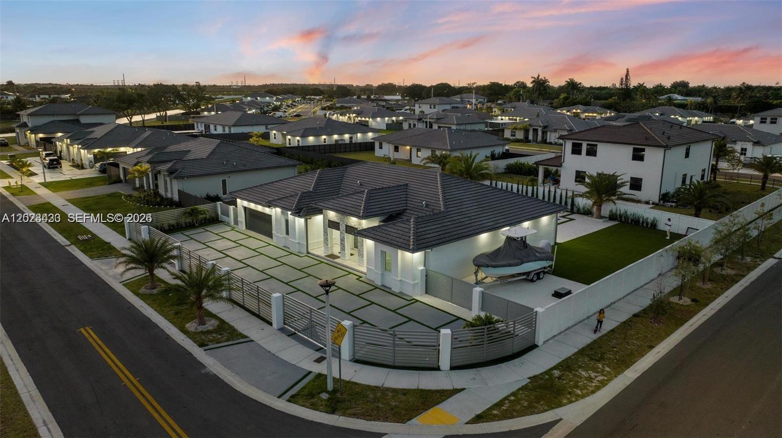 An aerial view shows a modern single-story house with a paved driveway and a boat — 13305 SW 190th Ter # 13305, Miami FL 33177, MIAMI, FL
